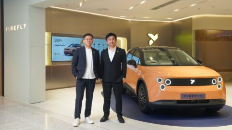 Firefly president Daniel Jin, left, poses with another man beside an orange Firefly EV at the Bangkok store.