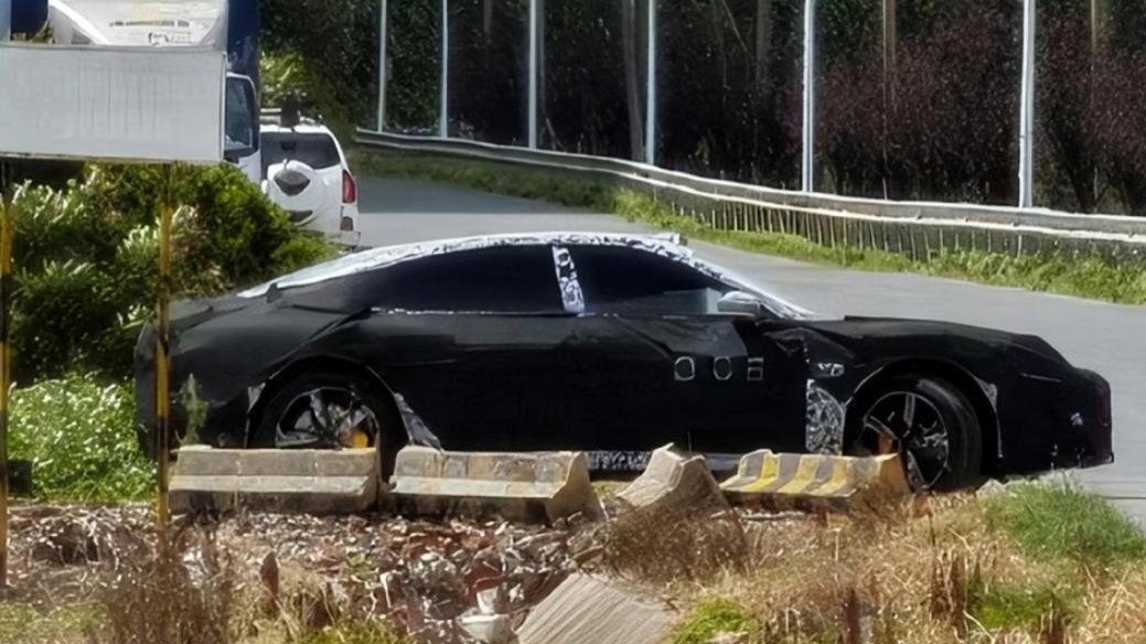 Side view of a camouflaged sedan with black body coverings and patterned wrap around the roof and pillars.