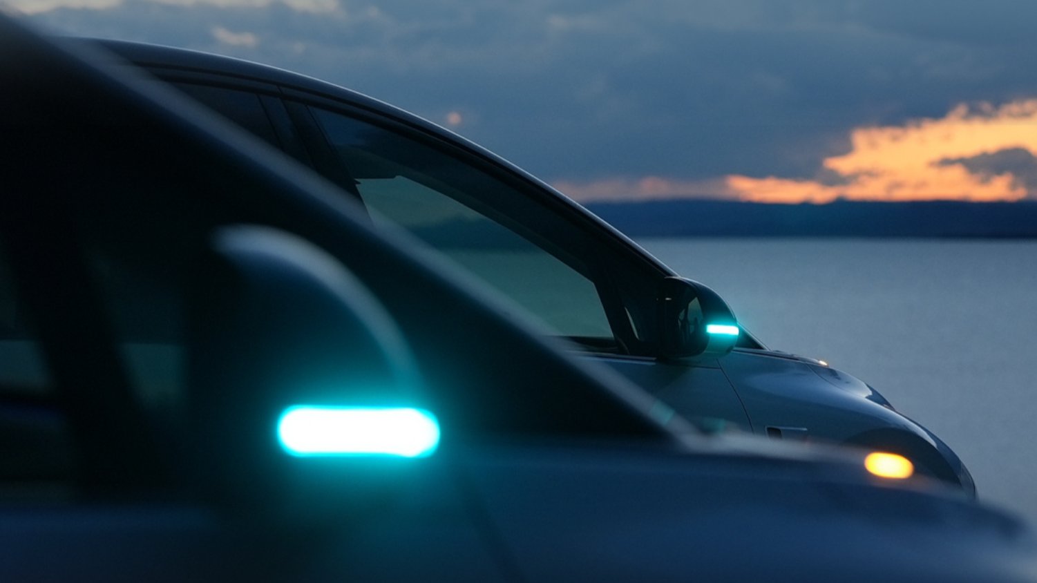 Turquoise driver-assistance indicator lights illuminated on the side mirrors of 2 Li Auto vehicles at dusk.